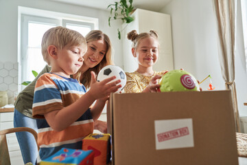 Mother looking at children putting toys in donation box