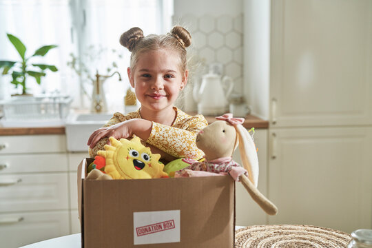 Smiling girl leaning on donation box at home