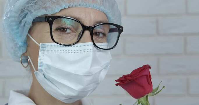 Roses for health day. A view of a doctor in protective uniform hold a nice red rose during quarantine time.