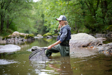 young woman fly fishing in a mountain river - 459408910
