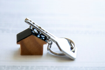 key with house keychain and coins on top of document