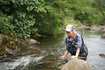 young woman fly fishing in a mountain river