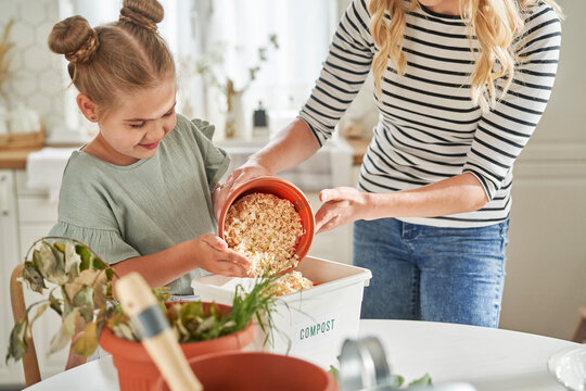 Mother teaching daughter to make compost at home