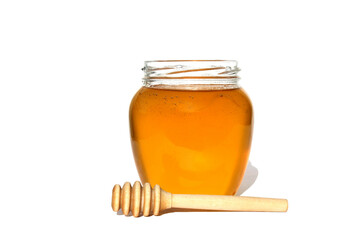 Glass jar with delicious fresh honey. There is a wooden ladle nearby. White isolated background.