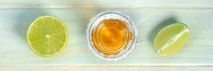 Tequila shot with lime slices panorama, a Mexican drink with a salt rim, overhead flat lay shot panoramic banner