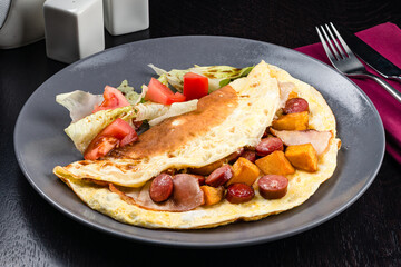 Fried eggs with sausages in olive oil. Hearty breakfast