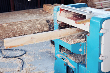 Fototapeta na wymiar A wood plate passing through the thickness planer machine in a carpentry workshop.