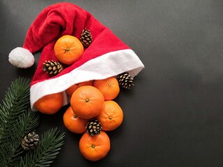 Christmas tangerines in a Santa hat on an black background, Christmas fruits, festive symbol, Merry Christmas, New Year and tangerines