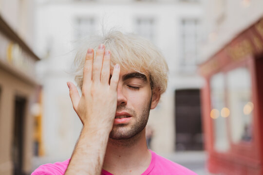 Young gay man with eyes closed covering face with hand