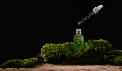 bottle of cosmetic serum on natural background with moss organic cosmetics