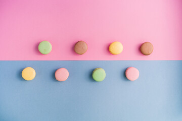 Studio shot of pastel colored macaroon cookies flat laid against pink and blue background