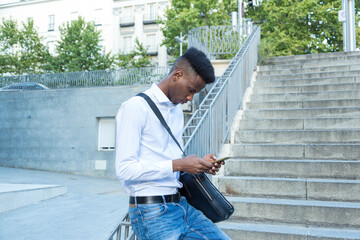 Obraz premium young african american business man on stairs typing message on mobile phone