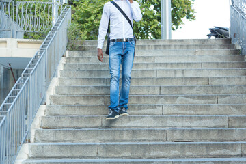 young black business man walking down stairs and talking on the phone