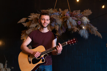 Fototapeta premium Male musician playing acoustic guitar. Guitarist plays classical guitar on stage in concert