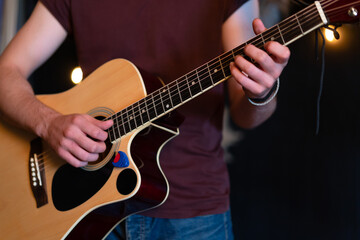 Male musician playing acoustic guitar. Guitarist plays classical guitar on stage in concert Close up