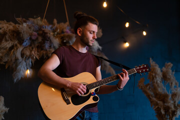 Male musician playing acoustic guitar. Guitarist plays classical guitar on stage in concert