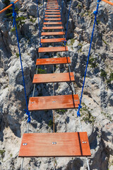 Suspension rope ladder in mountains over the chasm - 459415555