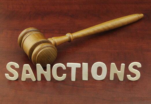 Judge Gavel And Word Sanctions On Wooden Table.	