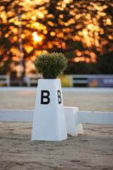 Dressage arena, close-up of the compass point B in portrait format, the sun rises in the...