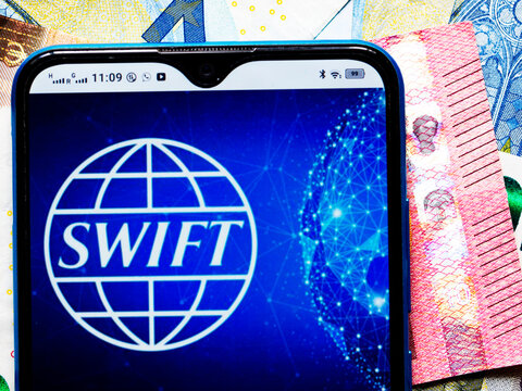In this photo illustration SWIFT logo seen displayed on a smartphone on the background of Euro bills