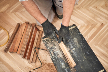 Repairman restoring old parquet hardwood floor.