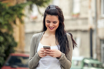 Young cute female using smartphone on the street.