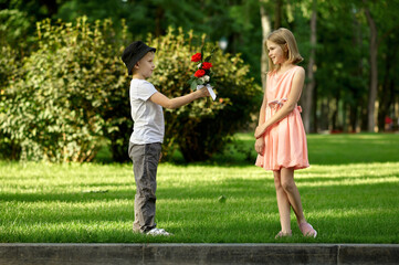 Obraz premium Children's date, boy gives flowers to girl
