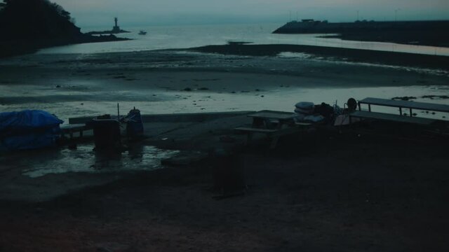 Wide Shot Of Some Rubbish Burning In A Steel Drum On The Beach At Dusk.