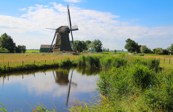 Water reflections of a historic windmill in a pond (near Workum, Frisia, Netherlands) - Powered by Adobe