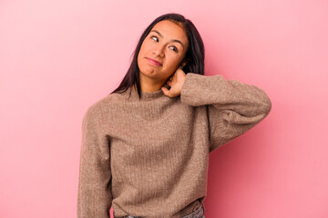 Young latin woman isolated on pink background  touching back of head, thinking and making a choice.