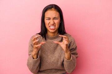 Young latin woman isolated on pink background  upset screaming with tense hands.