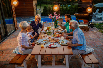 Three generations family family during dinner, celebrating holiday together in the backyard