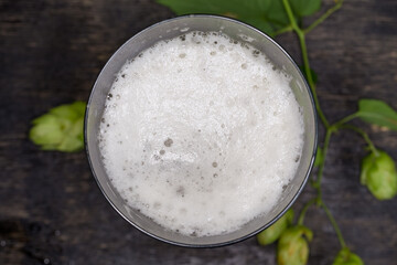 Glass with beer covered with foam, top view, selective focus