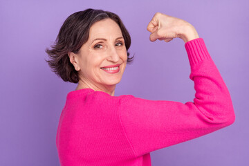 Profile side photo of aged woman happy smile show hand muscles strong isolated over violet color...