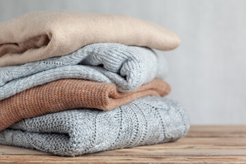 Pile of cozy knitted sweaters on a neutral background. Warm concept