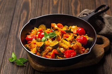 Sautéed Zucchini, Bell Pepper , Carrot and Onion with Tomato sauce on a dark wooden table. Close-up.