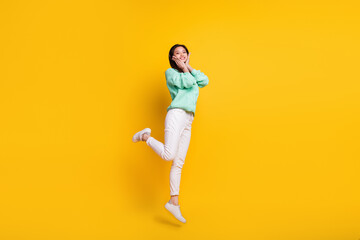 Fototapeta na wymiar Full size photo of pretty nice cute woman jump up air smile hold hands face cheeks isolated on yellow color background