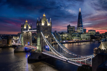 Elevated view to the illuminated Tower Bridge and urban skyline of London along the river Thames, UK, just after sunset