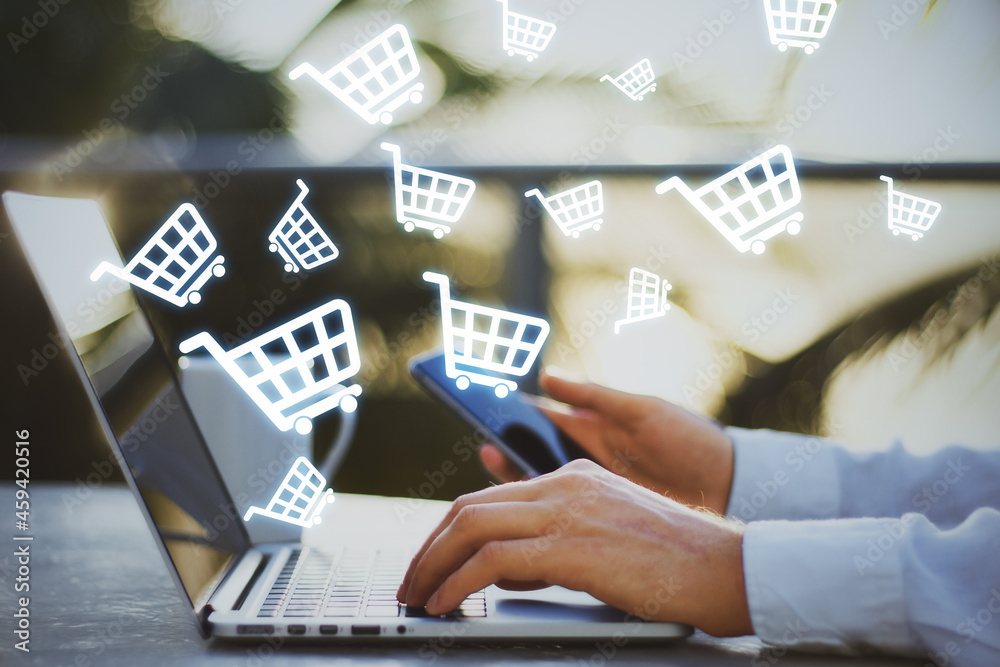 Poster close up of hands using laptop with abstract glowing cart icons on blurry background. online shoppin