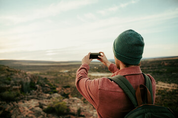 Caucasian male photographer hiking in wilderness taking images on cellular device 
