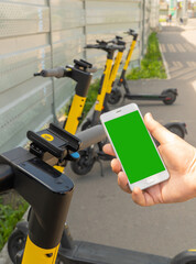 smartphone screen and electric scooter. Rent an street transport by scanning QR code. Payment for rental using a cell phone via a mobile application. scooter ready to scan and unlock