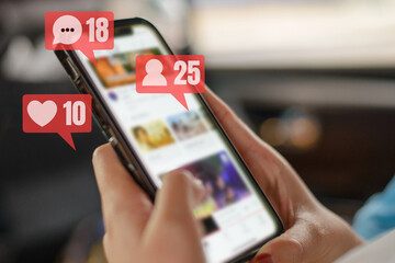 Woman's hand holding a smartphone connected to social media She's checking the likes and people comment on pubic post with notification icons of like, message, comment on smartphone screen.