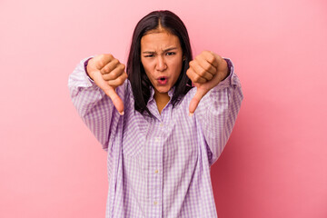 Fototapeta premium Young latin woman isolated on pink background showing thumb down and expressing dislike.