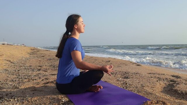 young woman meditating on sea beach