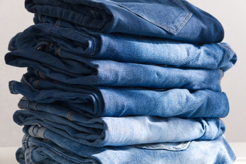 a pile of blue jeans on a light background. Sunlight. Close up - Powered by Adobe