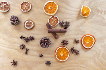 Christmas composition made of cones, dried oranges and lemons, cinnamon and anise stars. Plywood in the background.