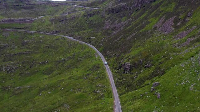 Drone shot following a van on Bealach Na Ba Applecross road through the mountains of the Applecross peninsula, in Wester Ross in the Scottish Highlands