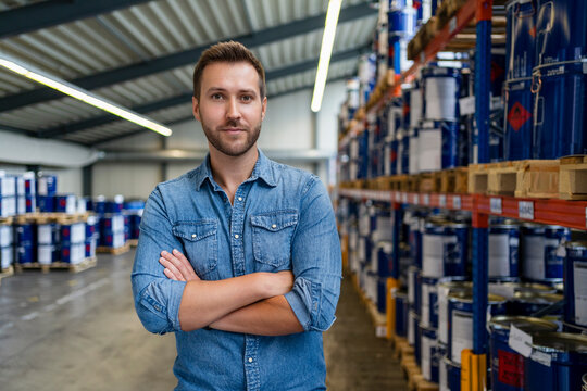 Businessman standing with arms crossed at paint warehouse