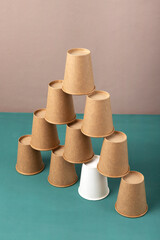 Vertical image of paper cup tower.Concept of ideas to accelerate growth on the green desk againt light background