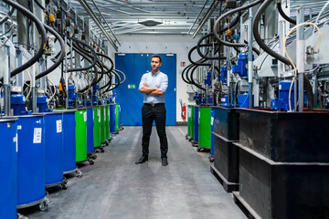 Businessman with arms crossed standing at paint production line